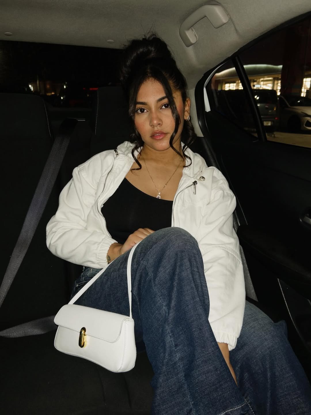 Daniela in the backseat with a white bag