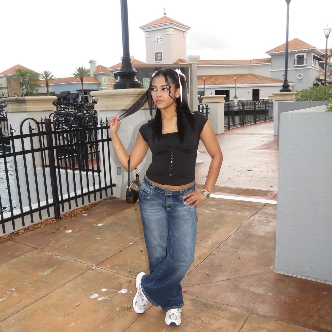 Daniela in black top and jeans, posing by a plaza
