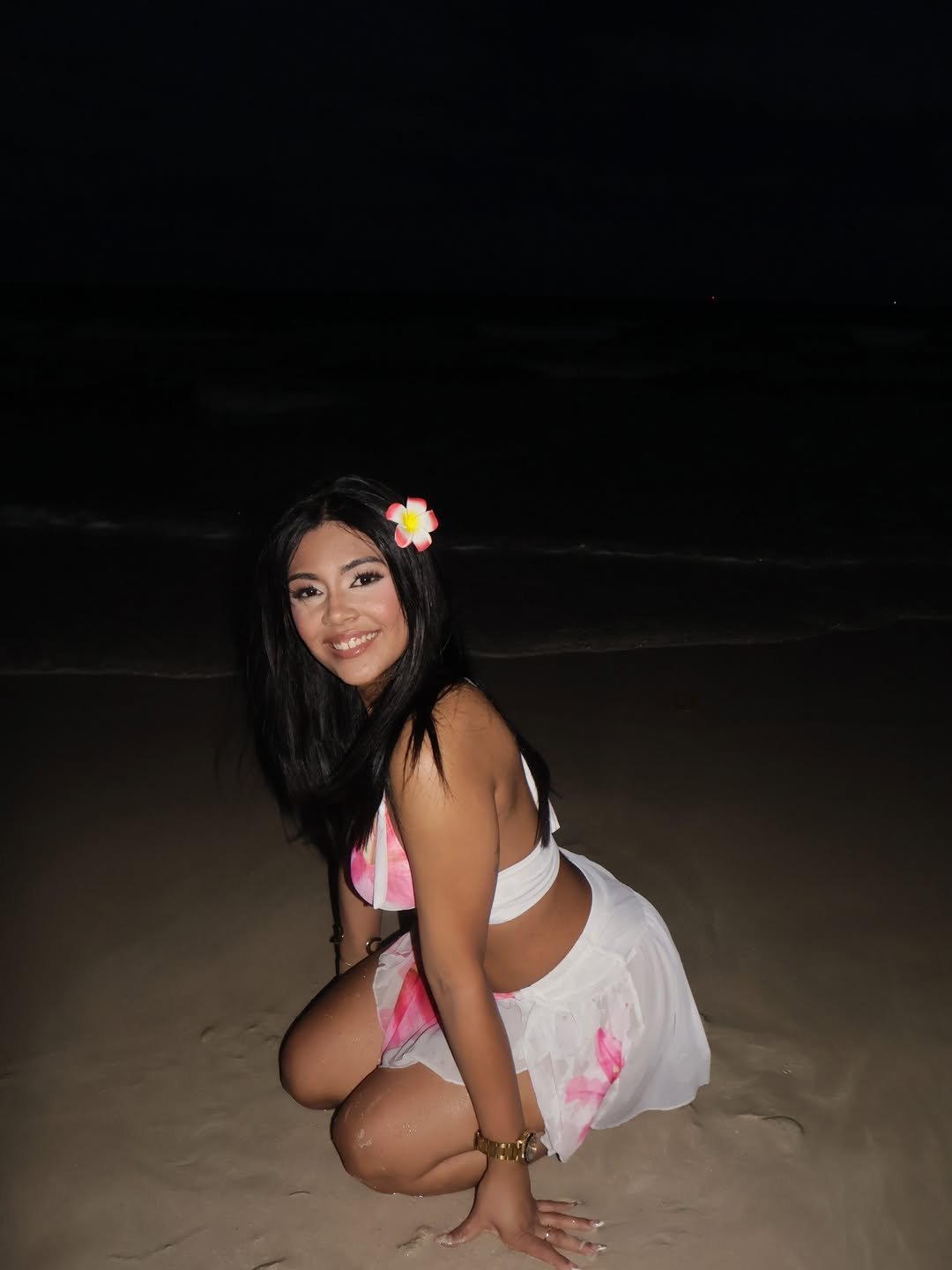 Daniela kneeling on the sand, smiling